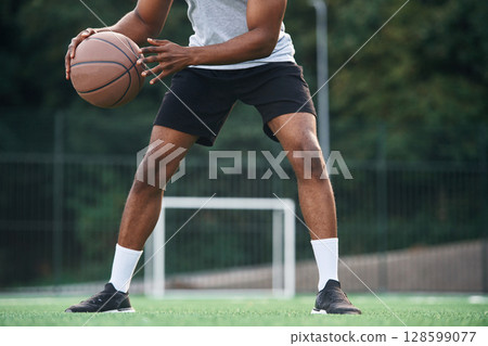 Close up view. Young black man is with basketball ball outdoors 128599077