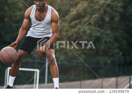 Front view. Young black man is with basketball ball outdoors 128599079
