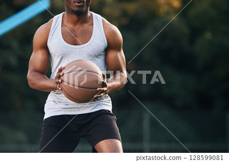 Front view. Young black man is with basketball ball outdoors 128599081