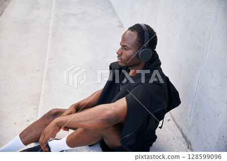 With headphones. Handsome black man is posing outdoors at daytime 128599096