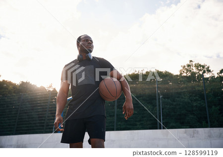 Confident person. Young black man is with basketball ball outdoors 128599119