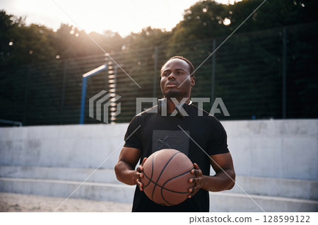 Confident person. Young black man is with basketball ball outdoors 128599122