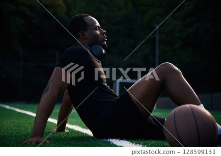 Sitting and relaxing. Young black man is with basketball ball outdoors Sitting and relaxing. Young black man is with basketball ball outdoors 128599131