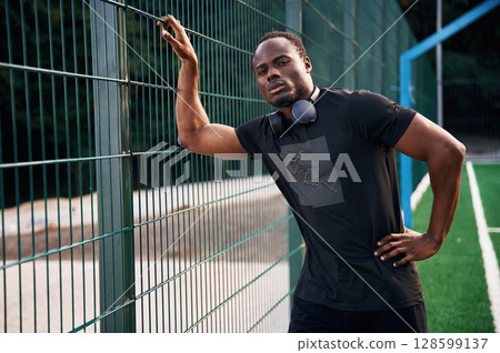 With headphones on the neck. Handsome black man is posing outdoors at daytime 128599137