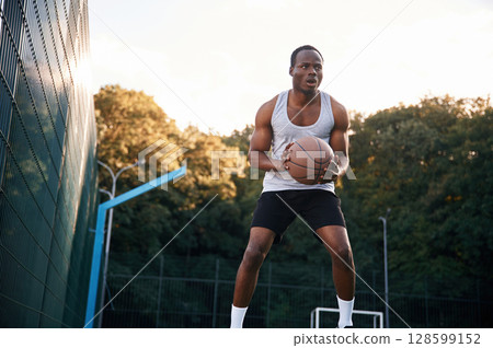 Photo in motion. Young black man is with basketball ball outdoors 128599152