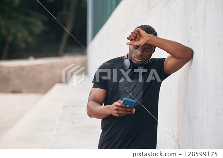 Posing and standing. Handsome black man is outdoors at daytime 128599175