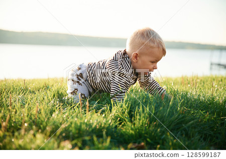 Cute little boy is having fun outdoors on the ground with green grass 128599187