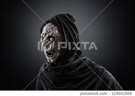 Portrait of a zombie with hooded cape over dark misty background Portrait of a zombie with hooded cape over dark misty background 128601068