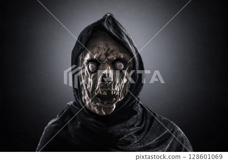 Portrait of a zombie with hooded cape over dark misty background 128601069