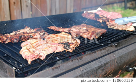 Juicy barbecue meat on the grill, close view, summer barbecue bliss background 128603139