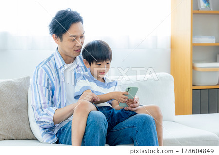 Dad and child looking at smartphone Dad and child looking at smartphone 128604849