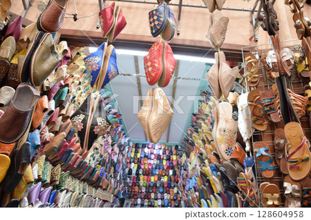 Slippers or sandals of many colors hung from street stalls in Marrakech's souk Slippers or sandals of many colors hung from street stalls in Marrakech's souk 128604958