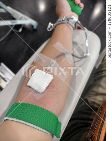 Close-Up of Blood Donation in Progress. Arm with Needle and Tubing 128605121