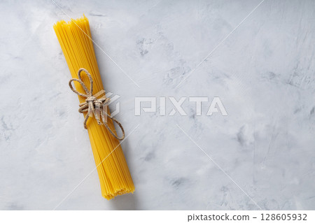 Raw Spaghetti Bundle Tied with Jute Twine on Concrete Surface Copy Space 128605932