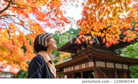Image of a woman looking at autumn leaves Background material AI generated material 128606544