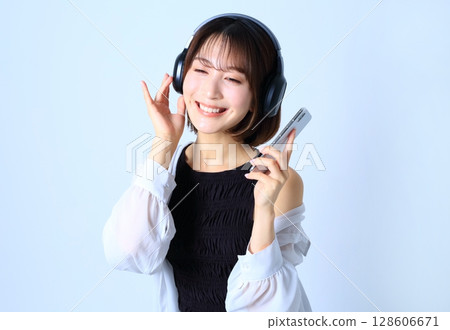一位女士正在用智慧型手機聽音樂的圖片 一位女士正在用智慧型手機聽音樂的圖片 128606671