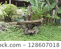 Unique outdoor sink crafted from natural, weathered wood branches with a modern stainless steel faucet in a lush green garden. Features a pond with an aerator and tropical plants in the background. 128607018