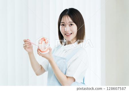 拿著牙刷和牙齒模型的牙科工作人員女士 128607587