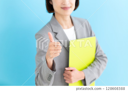 A middle-aged business woman wearing a gray suit and giving a thumbs up 128608388