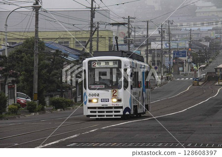 [Large logo blurred, difficult driver blurred] Streetcar leaving Yachigashira Station, Aoyagicho, Hakodate City 128608397
