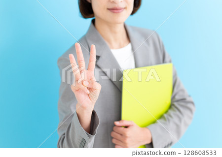 一位身穿灰色西裝的中年女商界女性舉起三根手指 128608533