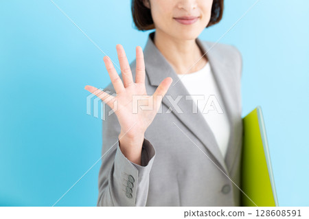 一位身穿灰色西裝、舉起五根手指的中年女商界女性 一位身穿灰色西裝、舉起五根手指的中年女商界女性 128608591
