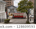 [Pedestrians blurred, passenger advertisements blurred] A streetcar passing through Hakodate Daisanzaka, Suehirocho, Hakodate City 128609593