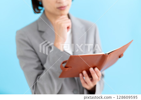 一位身穿西裝、手持筆記本的中年女商人 128609595