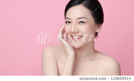 A beautiful young Asian woman with clean, fresh skin against a pink background. Skincare, facial treatment, cosmetology, beauty, and spa. An elegant portrait of an Asian woman. A beautiful young Asian woman with clean, fresh skin against a pink background. Skincare, facial treatment, cosmetology, beauty, and spa. An elegant portrait of an Asian woman. 128609914