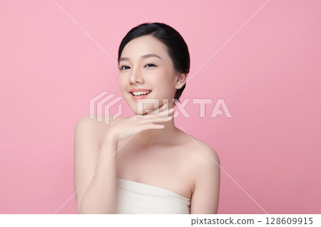 A beautiful young Asian woman with clean, fresh skin against a pink background. Skincare, facial treatment, cosmetology, beauty, and spa. An elegant portrait of an Asian woman. A beautiful young Asian woman with clean, fresh skin against a pink background. Skincare, facial treatment, cosmetology, beauty, and spa. An elegant portrait of an Asian woman. 128609915