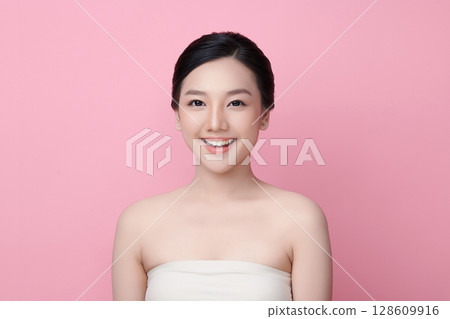 A beautiful young Asian woman with clean, fresh skin against a pink background. Skincare, facial treatment, cosmetology, beauty, and spa. An elegant portrait of an Asian woman. A beautiful young Asian woman with clean, fresh skin against a pink background. Skincare, facial treatment, cosmetology, beauty, and spa. An elegant portrait of an Asian woman. 128609916