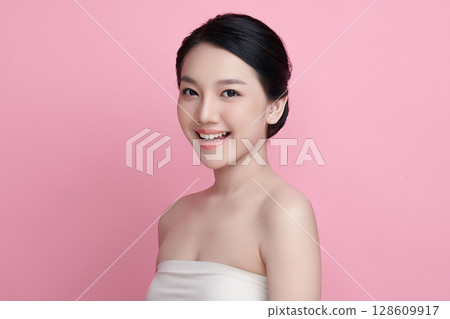 A beautiful young Asian woman with clean, fresh skin against a pink background. Skincare, facial treatment, cosmetology, beauty, and spa. An elegant portrait of an Asian woman. A beautiful young Asian woman with clean, fresh skin against a pink background. Skincare, facial treatment, cosmetology, beauty, and spa. An elegant portrait of an Asian woman. 128609917