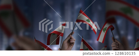 Lebanon flags in their hands on a blurred urban background 128610135