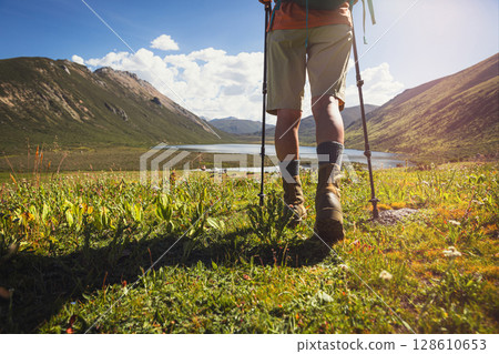 Female hiker wearing leather boots hiking on high altitude grassland mountains 128610653