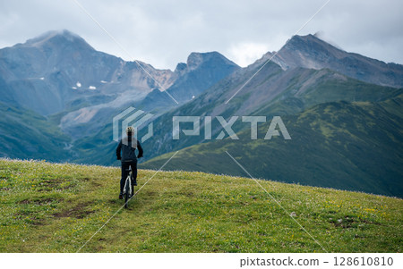 People riding mountain bike on flowering grassland mountain trail 128610810