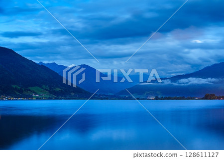 Tranquil Blue Hour Scene Serene Lake Reflecting Majestic Mountains and Cloudy Sky Vista 128611127