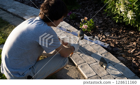 Laying paving stones on cement mortar. Laying a garden path made of tiles. Self-laying of concrete paving slabs in the courtyard of the house. do it yourself. DIY Laying paving stones on cement mortar. Laying a garden path made of tiles. Self-laying of concrete paving slabs in the courtyard of the house. do it yourself. DIY 128611160