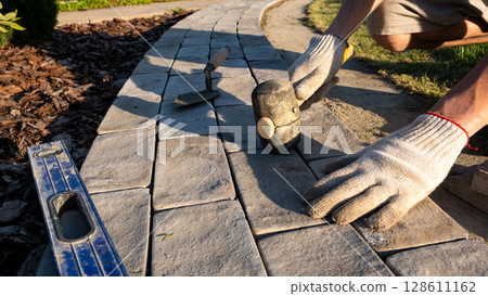 Laying paving stones on cement mortar. Laying a garden path made of tiles. Self-laying of concrete paving slabs in the courtyard of the house. do it yourself. DIY 128611162