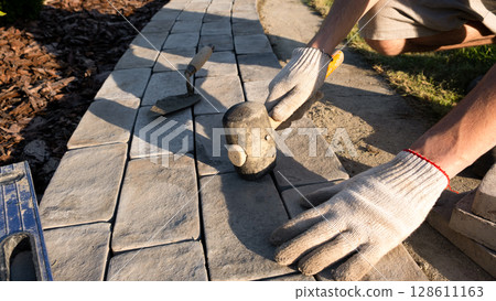 Laying paving stones on cement mortar. Laying a garden path made of tiles. Self-laying of concrete paving slabs in the courtyard of the house. do it yourself. DIY Laying paving stones on cement mortar. Laying a garden path made of tiles. Self-laying of concrete paving slabs in the courtyard of the house. do it yourself. DIY 128611163