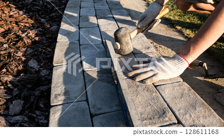 Laying paving stones on cement mortar. Laying a garden path made of tiles. Self-laying of concrete paving slabs in the courtyard of the house. do it yourself. DIY 128611168