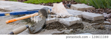 Laying paving stones on cement mortar. Laying a garden path made of tiles. banner, Self-laying of concrete paving slabs in the courtyard of the house. do it yourself. DIY 128611169