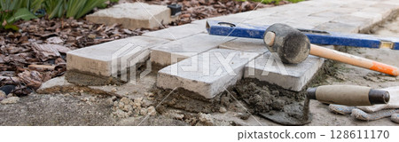 Laying paving stones on cement mortar. Laying a garden path made of tiles. Self-laying of concrete paving slabs in the courtyard of the house. do it yourself. DIY Laying paving stones on cement mortar. Laying a garden path made of tiles. Self-laying of concrete paving slabs in the courtyard of the house. do it yourself. DIY 128611170