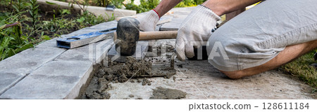 Laying paving stones on cement mortar. Laying a garden path made of tiles. Self-laying of concrete paving slabs in the courtyard of the house. do it yourself. DIY 128611184