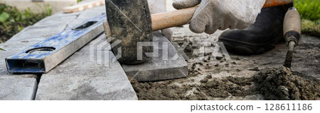 Laying paving stones on cement mortar. Banner, Laying a garden path made of tiles. Self-laying of concrete paving slabs in the courtyard of the house. do it yourself. DIY 128611186
