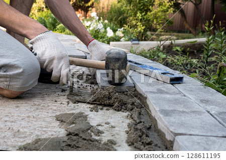 Laying paving stones on cement mortar. Laying a garden path made of tiles. Self-laying of concrete paving slabs in the courtyard of the house. do it yourself. DIY 128611195