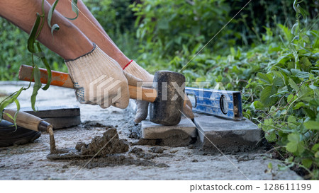 Laying paving stones on cement mortar. Laying a garden path made of tiles. Self-laying of concrete paving slabs in the courtyard of the house. do it yourself. DIY 128611199