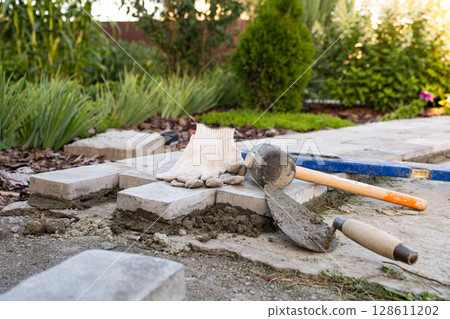 Laying paving stones on cement mortar. Laying a garden path made of tiles. Self-laying of concrete paving slabs in the courtyard of the house. do it yourself. DIY Laying paving stones on cement mortar. Laying a garden path made of tiles. Self-laying of concrete paving slabs in the courtyard of the house. do it yourself. DIY 128611202