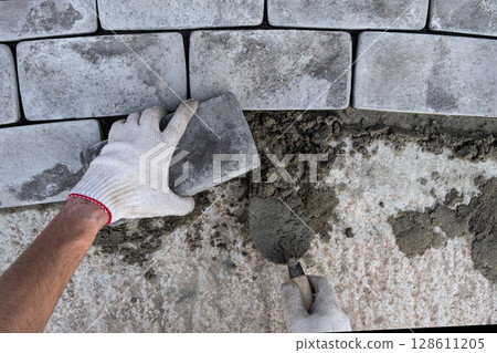 Laying paving stones on cement mortar. Laying a garden path made of tiles. Self-laying of concrete paving slabs in the courtyard of the house. do it yourself. DIY 128611205