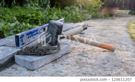 Laying paving stones on cement mortar. Laying a garden path made of tiles. Self-laying of concrete paving slabs in the courtyard of the house. do it yourself. DIY 128611207