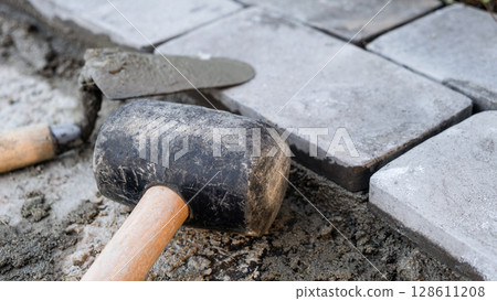 Laying paving stones on cement mortar. Laying a garden path made of tiles. Self-laying of concrete paving slabs in the courtyard of the house. do it yourself. DIY 128611208
